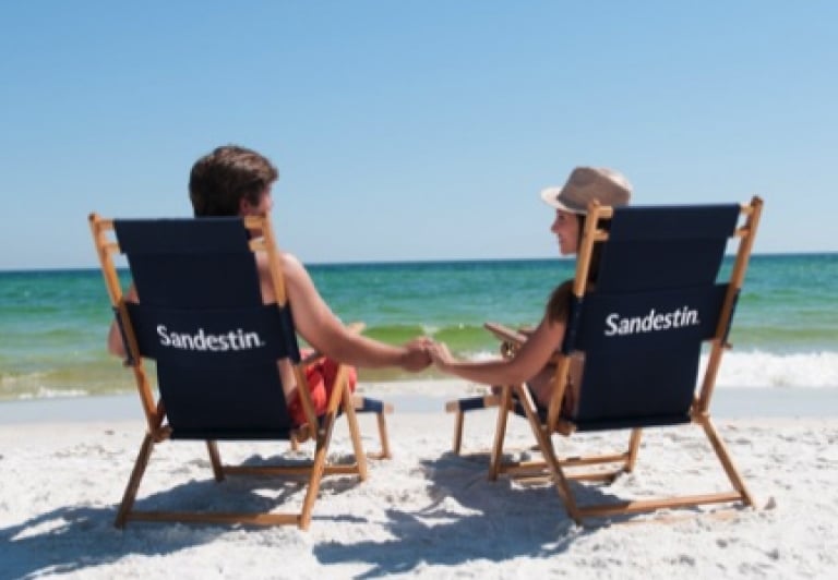 A couple relaxes on the beach in Sandestin beach chairs