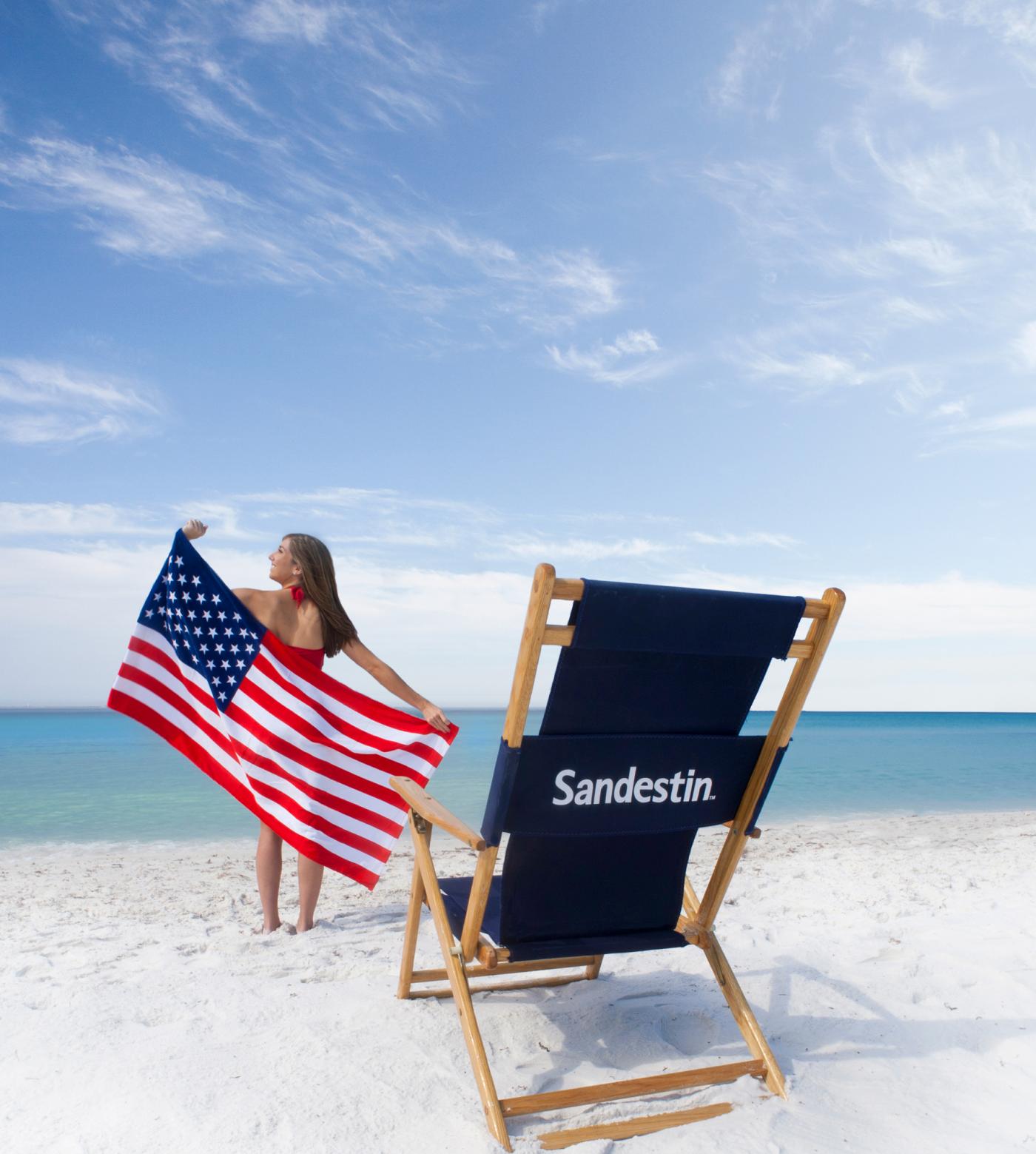 Woman on the beach with an American flag and beach chair