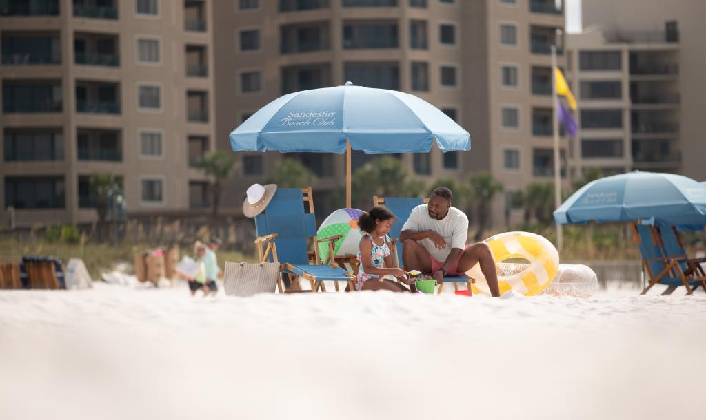 Father and Daughter playing in the sugar white sands of the Emerald Coast at the Beach Club of Sandestin.