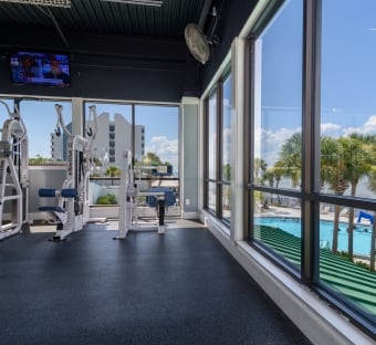 fitness equipment in front of a large window overlooking a pool